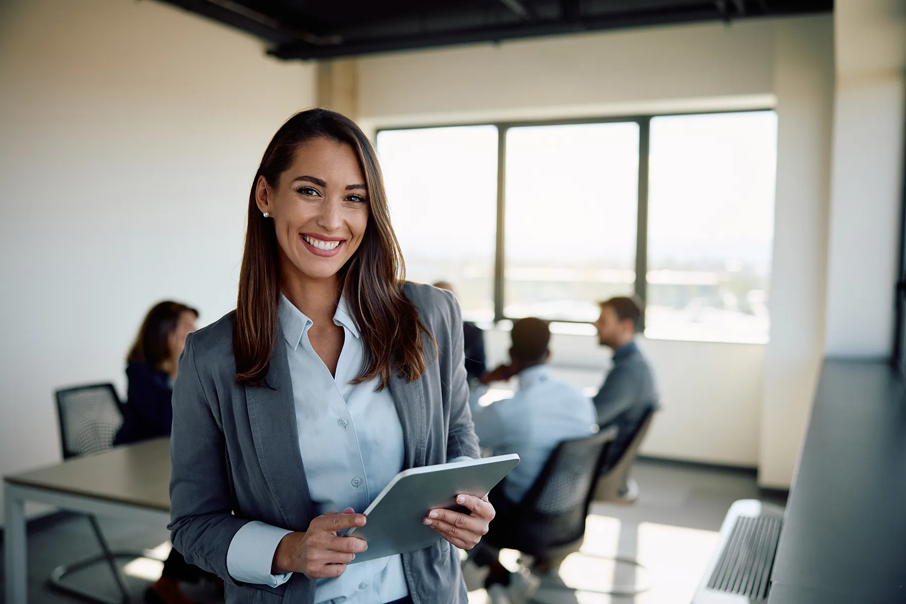 Happy businesswoman with touchpad in the office looking at camera.