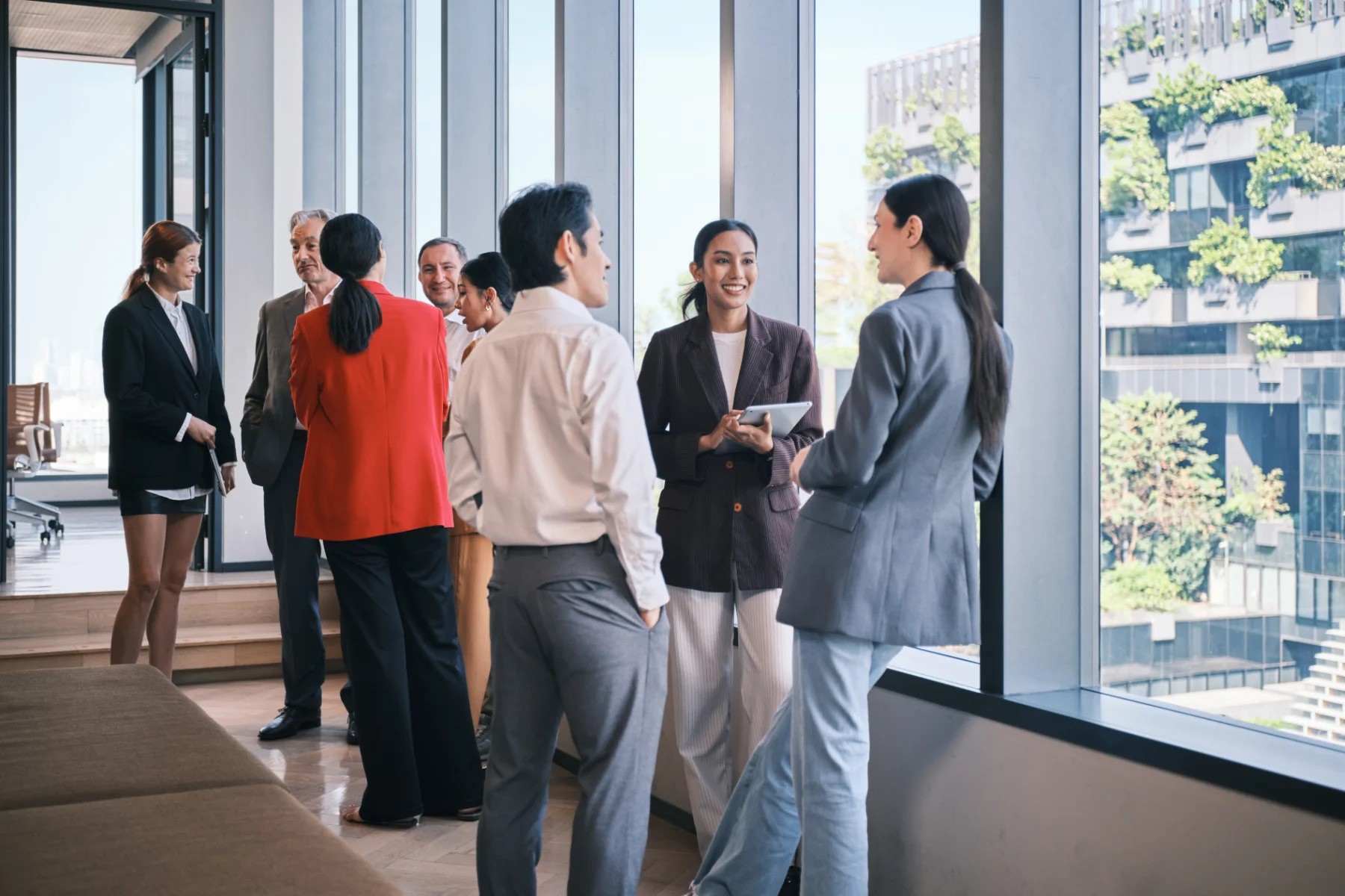 business-professionals-office-windows-city-view-hmg-plus. Group of business professionals talking by office windows with a city view
